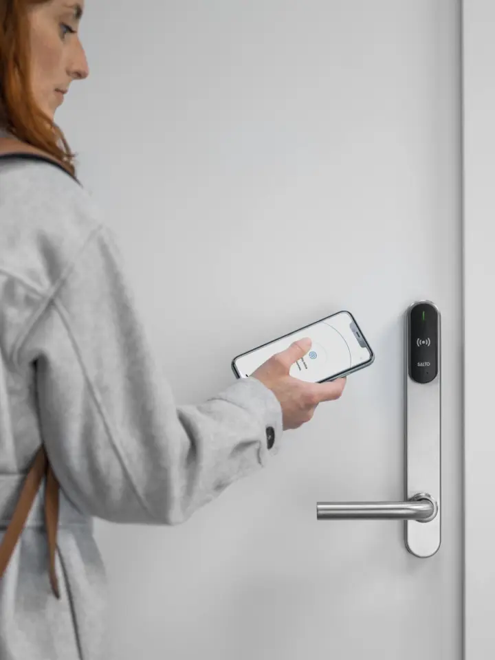 Person in light gray coat using phone to unlock apartment door | Salt Lake City Apartments