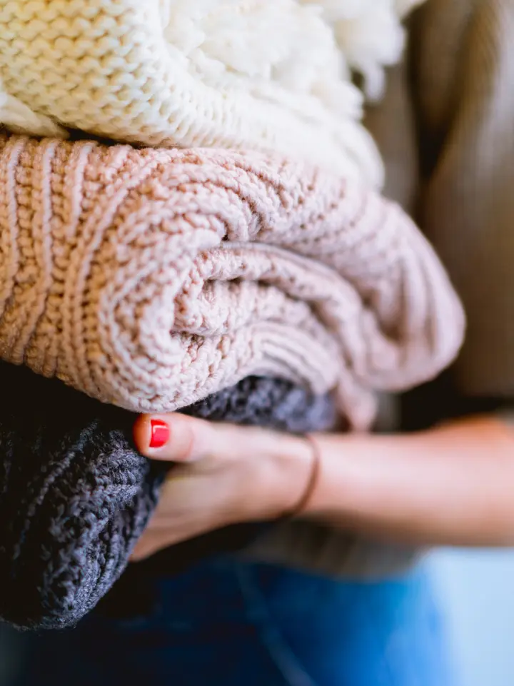 Person holding three quilted blankets charcoal, rose pink, and cream | Salt Lake City Apartments